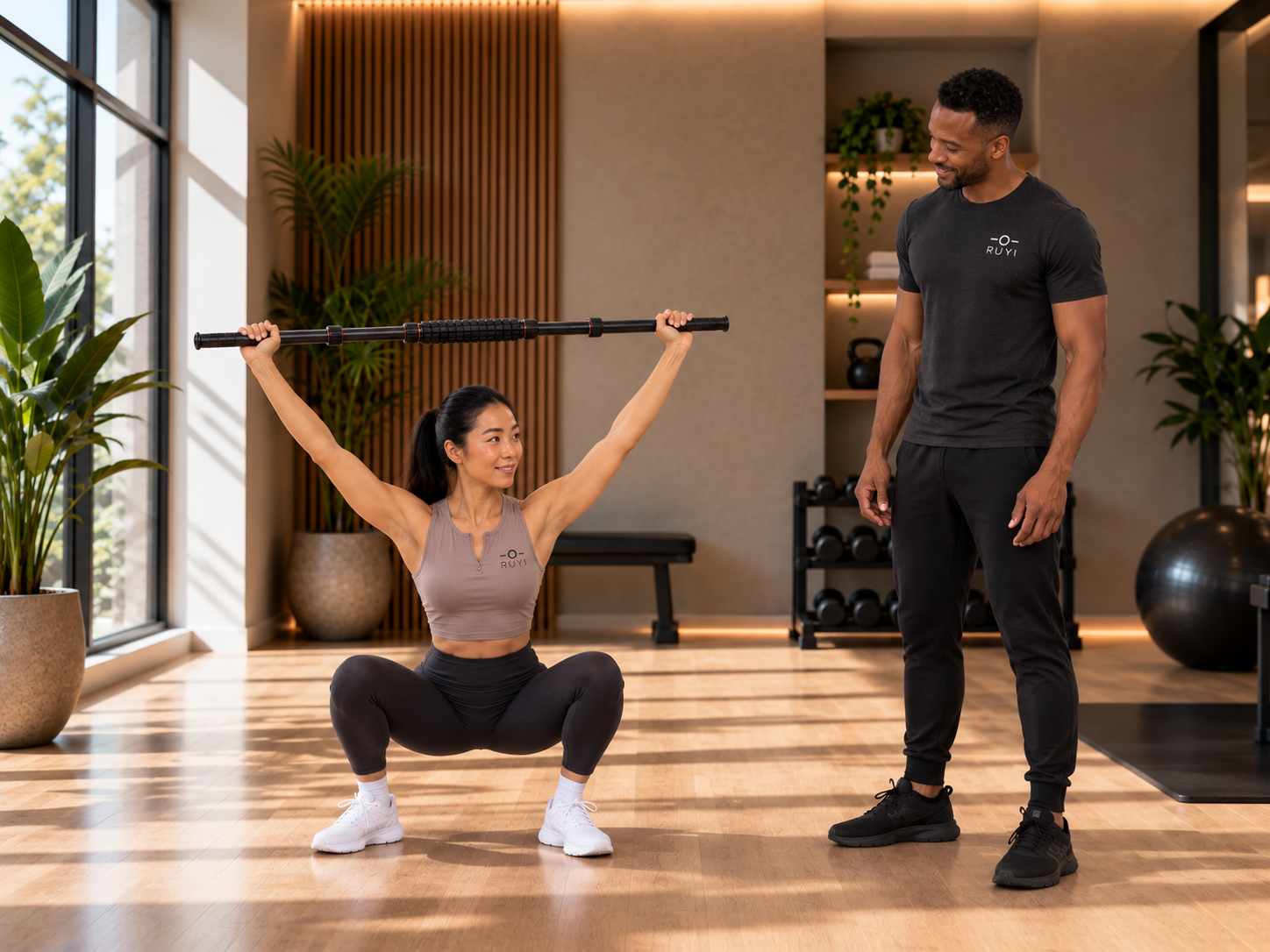 Woman holding RUYI overhead during a squat with a coach